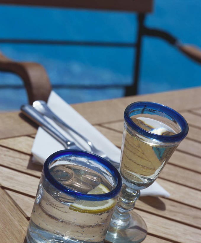 无人,游泳池,竖图,俯视,室外,特写,白天,水,桌面,桌子,杯子,餐具,椅子,朦胧,模糊,木制,叉子,刀叉,刀子,碟子,高脚杯,盘,木椅,水池,水面,两杯,泳池,玻璃制品,盘子,酒杯,木制品,碟,餐刀,餐叉,鸡尾酒杯,玻璃杯,进餐用具,彩图,高角度拍摄