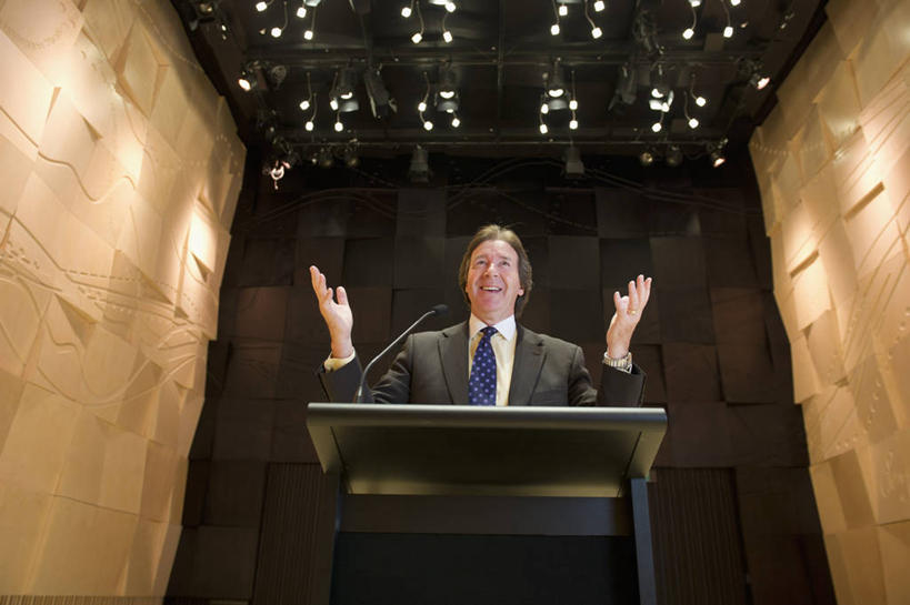 西方人,一个人,商务人士,商务男性,站,举,笑,微笑,露齿笑,横图,室内,白天,仰视,衬衫,照明,欧洲,欧洲人,仅一个男性,仅一个人,许多,阴影,套装,光线,影子,墙,灯光,领带,注视,顶灯,墙壁,墙面,灯,话筒,讲台,灯具,观察,看,托,演讲,站着,仅一个老年男性,报告,观看,照亮,察看,麦克风,象征,演说,庄重,照明设备,关注,扩音器,演说台,商务装,身份,宣传,传声器,工薪阶层,演讲台,正式,地位,微音器,鼓动,讲演,老年男性,男人,男性,白种人,白领,上班族,举起,举手,举着,向上举,向上伸,向上托,站立,半身,彩图,低角度拍摄,衬衣