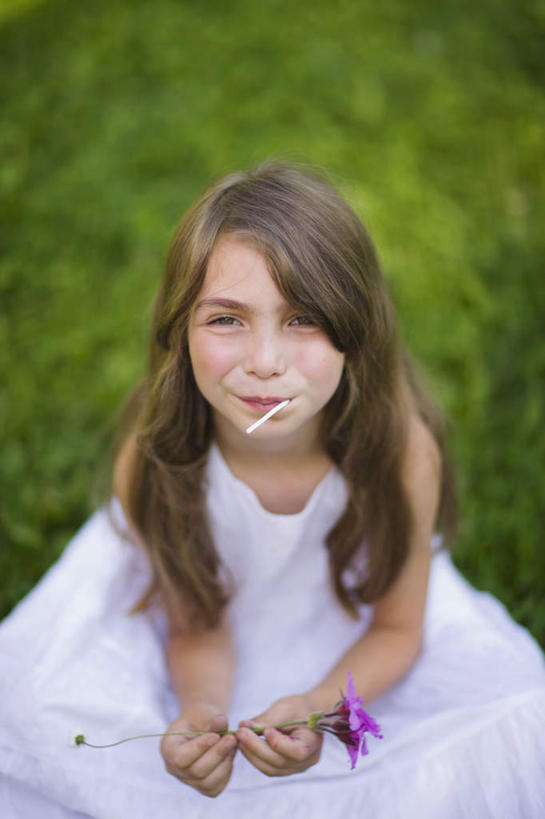 西方人,儿童,一个人,坐,吃,竖图,俯视,室外,白天,裙子,纯洁,草地,草坪,植物,欧洲,欧洲人,仅一个女性,仅一个人,握,阴影,连衣裙,朦胧,模糊,盛开,光线,棒棒糖,影子,食品,糖,糖果,甜点,甜品,拿,花蕾,拿着,注视,草,花,花瓣,花朵,鲜花,食物,一朵,小孩,绿色,紫色,白色,阳光,甜食,花苞,花蕊,看,仅一个小孩,可爱,童年,童趣,握着,关注,童真,烂漫,无邪,天真,女孩,女人,女性,白种人,孩子,嚼,食,抬头,仰头,坐着,半身,彩图,高角度拍摄,女生