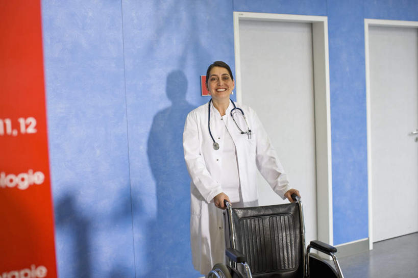 西方人,一个人,医生,医院,站,笑,微笑,露齿笑,横图,室内,白天,正面,工作服,制服,门,欧洲,欧洲人,仅一个女性,仅一个人,握,工具,墙,拿,拿着,注视,墙壁,墙面,轮椅,听诊器,门框,复健,观察,看,站着,仅一个中年女性,医护人员,医疗人员,康复,器械,握着,观看,察看,医疗设备,关注,医疗器械,医疗工具,医疗机构,辅助设备,工作制服,检测工具,女人,女性,中年女性,白种人,大夫,站立,半身,彩图,工作套服,病院,诊所