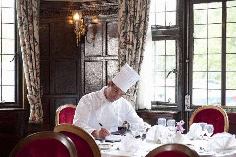 西方人,一个人,厨师,宾馆,坐,横图,室内,白天,正面,工作服,制服,餐桌,窗户,窗帘,桌子,酒店,帽子,椅子,照明,欧洲,欧洲人,仅一个男性,仅一个人,仅一个中年男性,许多,握,写字,装饰,笔,壁灯,布料,灯光,办公用品,折叠,拿,布纹,拿着,注视,水笔,玻璃窗,菜单,灯,文具,桌布,排列,红色,白色,帘子,餐巾,学习用品,灯具,台布,观察,看,遮阳,握着,餐台,观看,华丽,修饰,文具用品,照亮,点缀,察看,书写,照明设备,队列,关注,厨师帽,衬托,美观,雅致,雅观,工作制服,保洁方巾,口布,男人,男性,中年男性,白种人,厨师长,厨子,大厨,主厨,坐着,半身,彩图,工作套服,客店,客栈,旅店,旅馆,旅舍,汽车旅馆