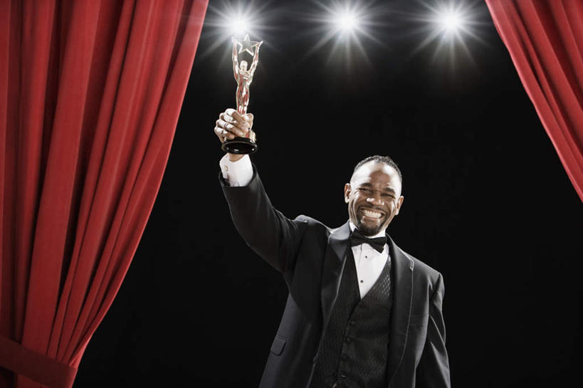 西方人,一个人,站,举,笑,微笑,露齿笑,横图,室内,白天,正面,西装,成功,胜利,照明,欧洲,非洲,黑人,欧洲人,仅一个男性,仅一个人,仅一个中年男性,一排,握,套装,正装,整齐,领结,灯光,拿,拿着,注视,职业装,灯,排列,灯具,观察,看,托,站着,射灯,光彩,握着,帷幕,观看,照亮,三盏,察看,象征,庄重,照明设备,队列,关注,帷幔,身份,幕布,荣誉,幕帘,奖品,正式,地位,荣耀,帷幔布,光荣,男人,男性,中年男性,非洲人,举起,举手,举着,向上举,向上伸,向上托,站立,半身,彩图,奖杯