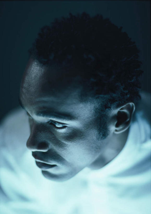 西方人,脸,头,脸颊,头发,一个人,笑,微笑,竖图,俯视,室内,特写,白天,欧洲,非洲,黑人,欧洲人,仅一个男性,仅一个人,黑色背景,服装,注视,休闲装,仅一个年轻男性,衣服,白色,黑色,观察,看,转头,休闲,休闲服,摄影,服饰,影棚,观看,察看,关注,男人,男性,年轻男性,非洲人,头部,卷发,脸部,脸蛋,面部,半身,彩图,高角度拍摄,影棚拍摄,拍摄