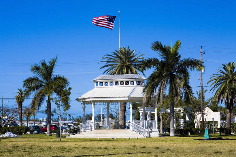 无人,横图,室外,白天,正面,旅游,度假,草地,草坪,岛屿,植物,标志建筑,地标,建筑,棕榈树,旗帜,国旗,叶子,美国,一面,阴影,飘扬,光线,影子,绿叶,娱乐,建设,星条旗,草,树,树木,蓝色,绿色,蓝天,天空,阳光,自然,天,享受,休闲,嫩叶,旅游胜地,放松,美国国旗,生长,晴朗,成长,飘逸,北美,北美洲,飞扬,美洲,棕榈叶,佛罗里达,佛罗里达州,佛州,阳光州,万里无云,北亚美利加洲,亚美利加洲,叶,叶片,旗,列岛,群岛,诸岛,晴空,晴空万里,彩图,美利坚合众国国旗,基韦斯特,基维斯特,西礁岛