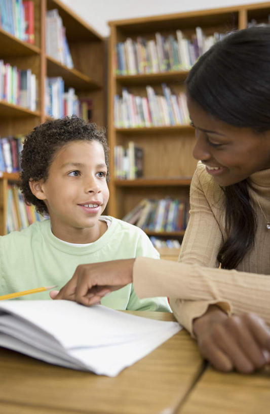 西方人,儿童,两个人,学生,教师,图书馆,坐,笑,微笑,露齿笑,竖图,室内,白天,正面,桌子,书籍,欧洲,非洲,黑人,欧洲人,指,服装,扭头,注视,休闲装,方向,书桌,小孩,衣服,课桌,观察,看,手势,转头,休闲,休闲服,服饰,观看,察看,指向,食指,关注,浏览室,男孩,男人,男性,年轻女性,女人,女性,非洲人,孩子,讲师,教授,老师,书,图书,坐着,半身,彩图,书库,图书库,阅览室,男生